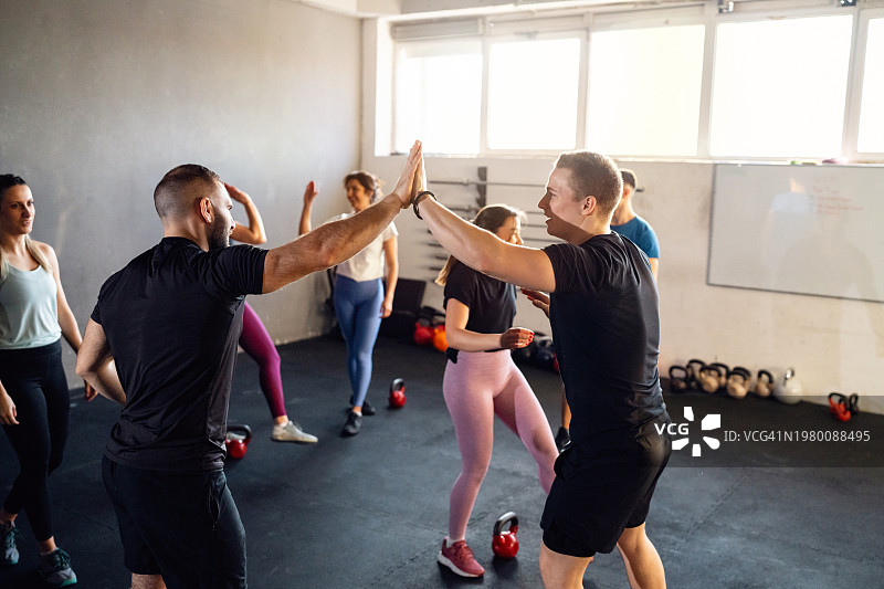 一群人在运动后与交叉训练器击掌图片素材