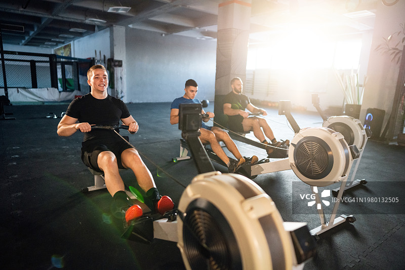 男人们在健身房的划船机上锻炼图片素材