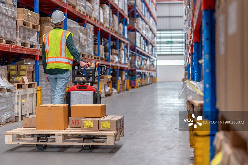 仓库内部：纸箱货架、工人扫描分拣包裹、托盘车移动库存图片素材