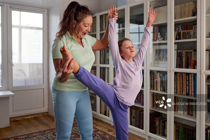 奶奶在家中书柜前与孙女一起做运动图片素材