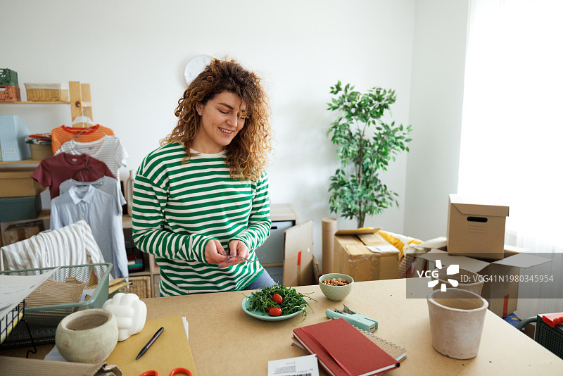年轻漂亮的女人在她的工作室享用早餐图片素材