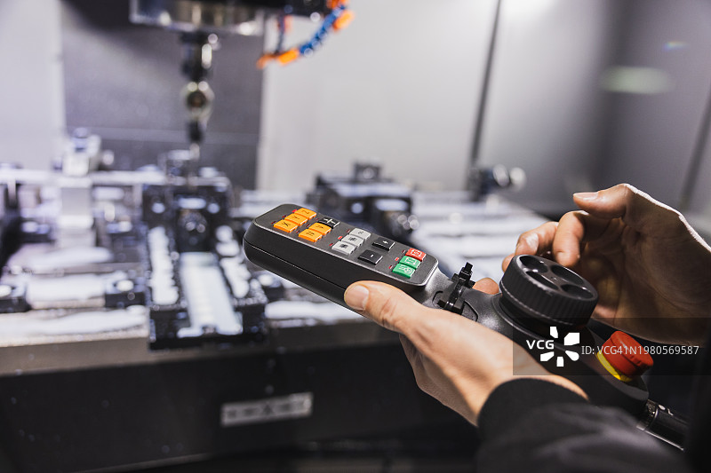 操作员熟练地使用遥控器在工业环境中操作精密机械图片素材