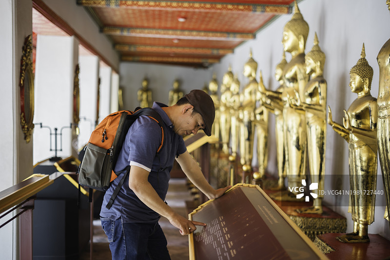 男人看着泰国曼谷卧佛寺的金色佛像图片素材