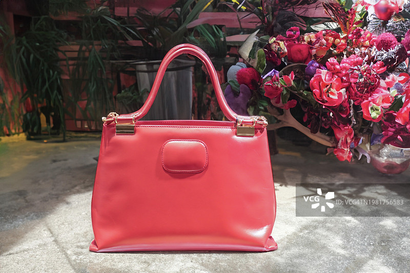花丛中的鲜红色皮革手提包图片素材