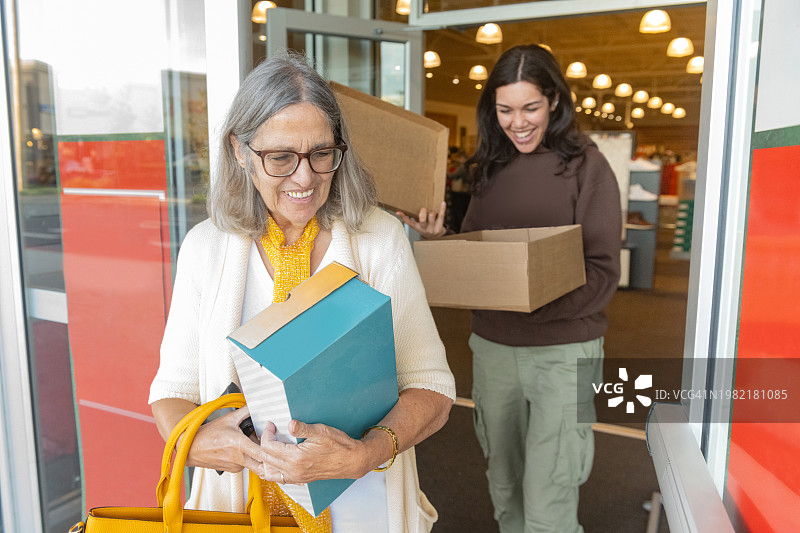 微笑的西班牙裔妇女走出佛罗里达州奥兰多市的鞋店图片素材