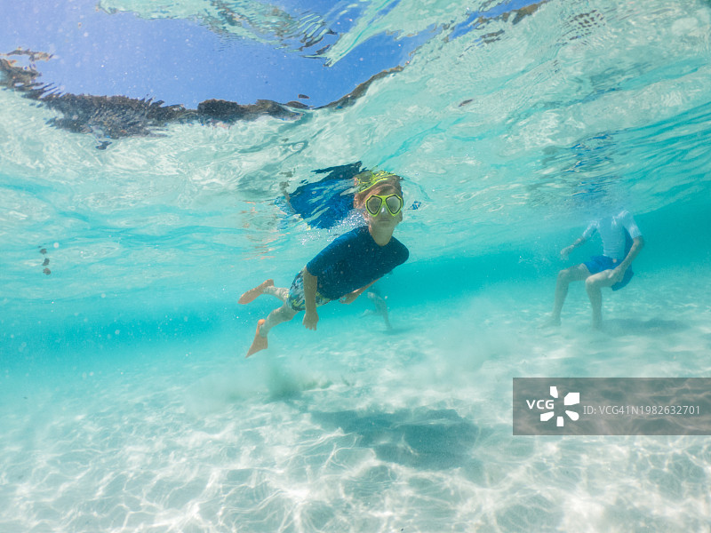 在清澈的蓝色海水中游泳和浮潜的青少年图片素材