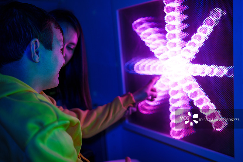 轮椅使用者和助手享受互动式LED灯光游戏图片素材