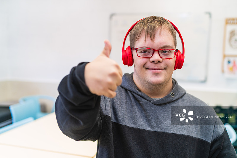 课堂上竖起大拇指的唐氏综合征青年图片素材