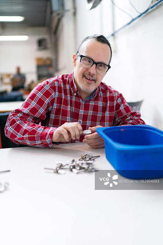 职业工坊中操作金属零件的唐氏综合征工人图片素材