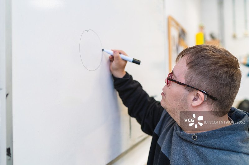 患有唐氏综合征的学生在白板上开始上课图片素材