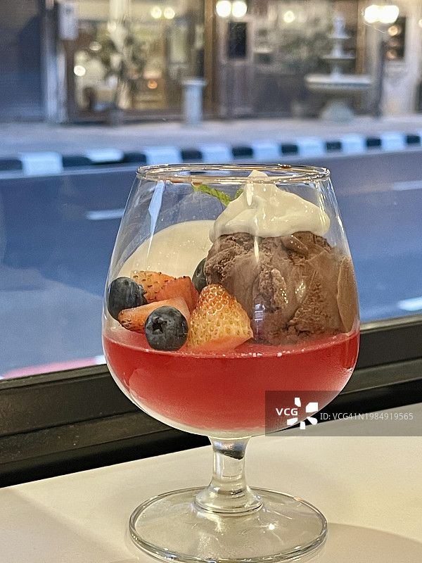 葡萄酒杯甜点 - 巧克力冰淇淋，红色果冻底座上放着水果片图片素材
