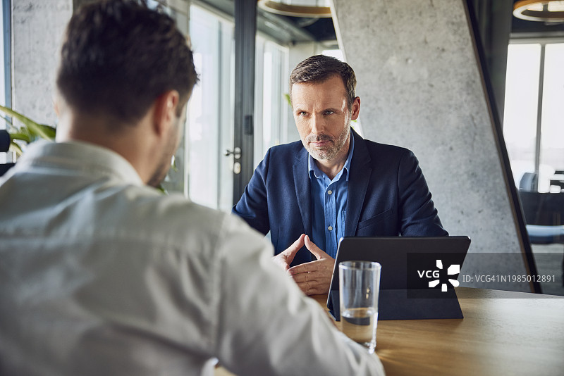 严肃的招聘人员在办公桌前面试候选人图片素材