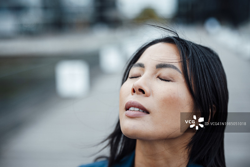 闭着眼睛，留着黑色头发的商务女人图片素材