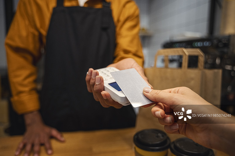 顾客在咖啡馆使用信用卡支付图片素材