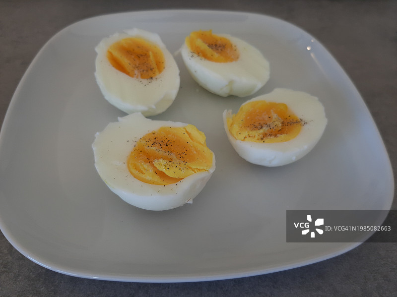 摆放在白色盘子里的两片煮鸡蛋图片素材