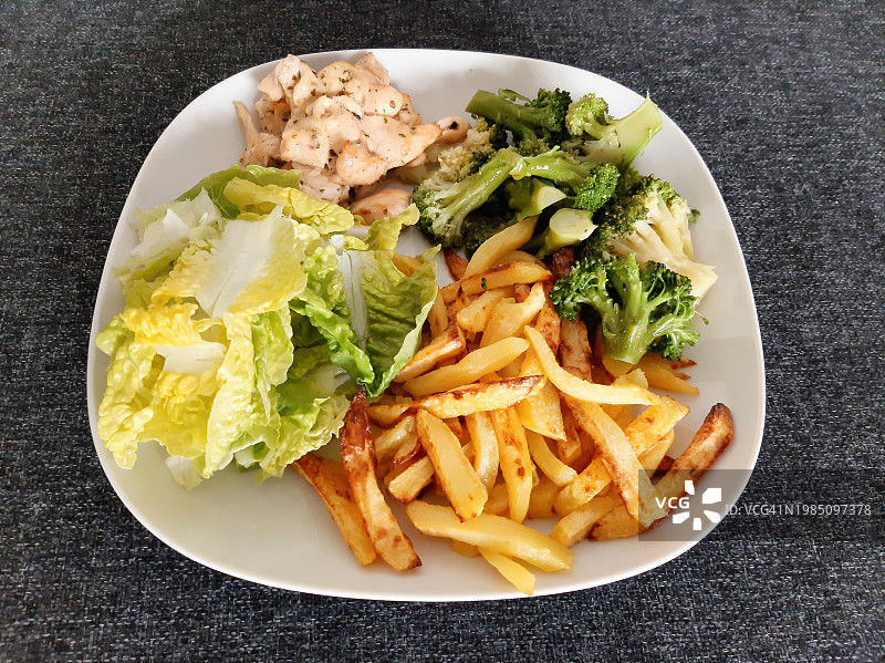 自制烤鸡配炸薯条、西兰花和绿色沙拉，放在白色盘子里图片素材