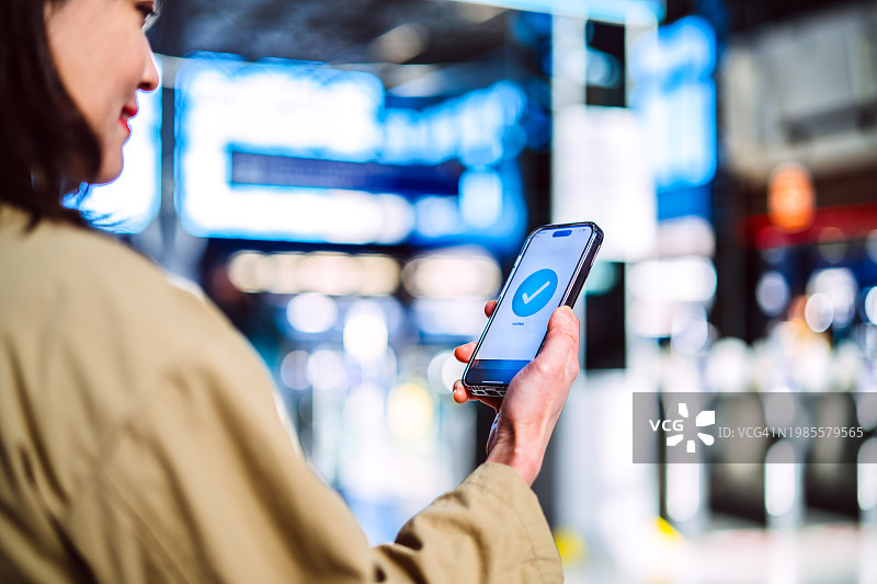快乐的亚洲女商人使用手机App在机场确认旅行行程图片素材