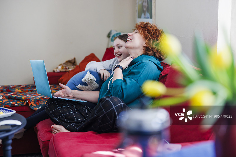 母女在舒适的客厅里视频通话欢笑图片素材