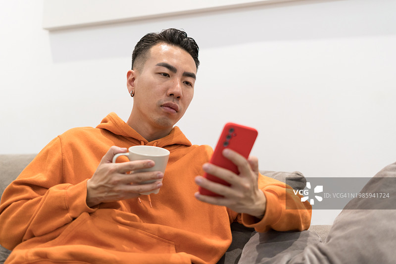 男性在家使用手机，悠闲地喝着咖啡图片素材