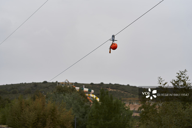 低角度拍摄：公共公园的滑索，头盔悬挂，天空为背景图片素材