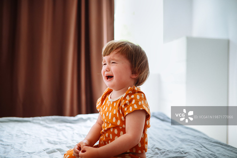 穿着睡衣在床上哭闹的幼儿：负面情绪和疲惫图片素材