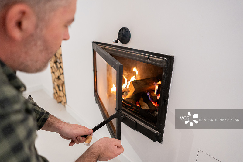 用拨火棍在壁炉里拨火的白人男子图片素材
