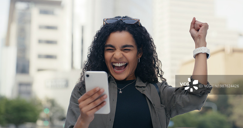 女人在城市中使用智能手机庆祝线上竞赛中奖，获得折扣或促销图片素材