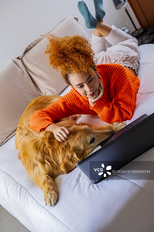 在电脑旁和她的狗在一起的拉丁妇女图片素材