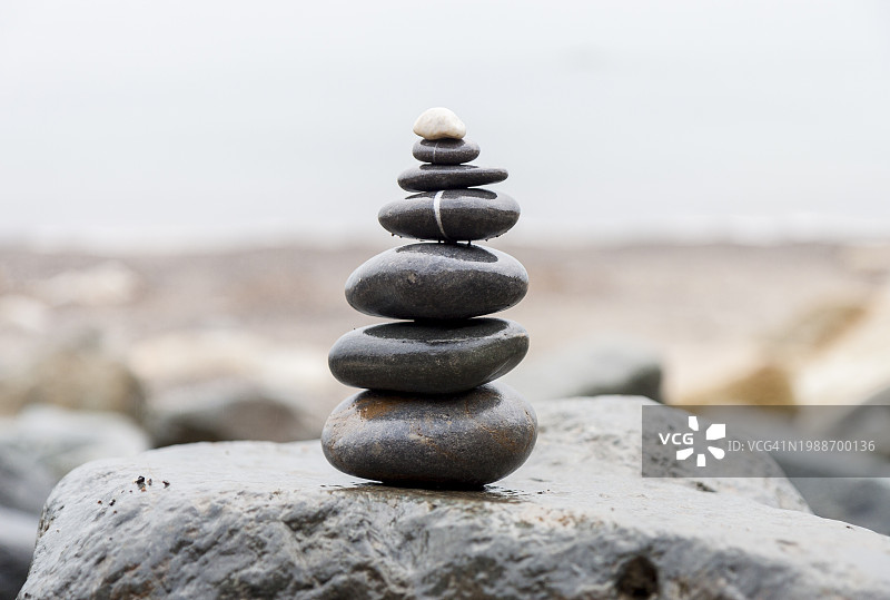 沿岩石海滩堆叠的鹅卵石，用于水疗、平衡、冥想和禅意主题的背景图片素材