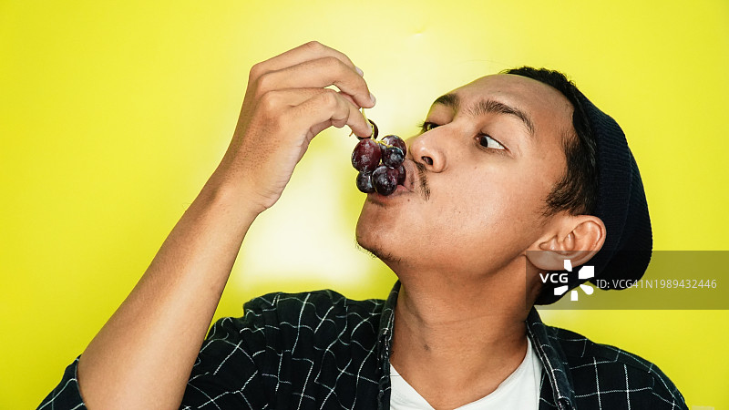 男人吃葡萄的侧面图图片素材
