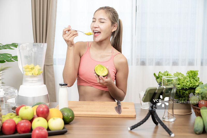 一位美丽健康的年轻女人在家搅拌牛油果冰沙，呵护健康图片素材