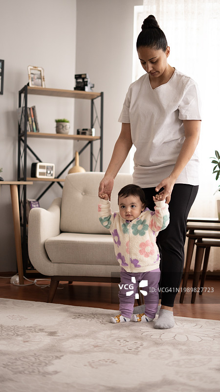 年轻的母亲在家教可爱的女儿走路图片素材