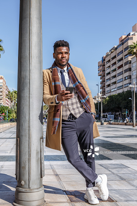 倚靠立柱使用手机的非裔美国高管图片素材