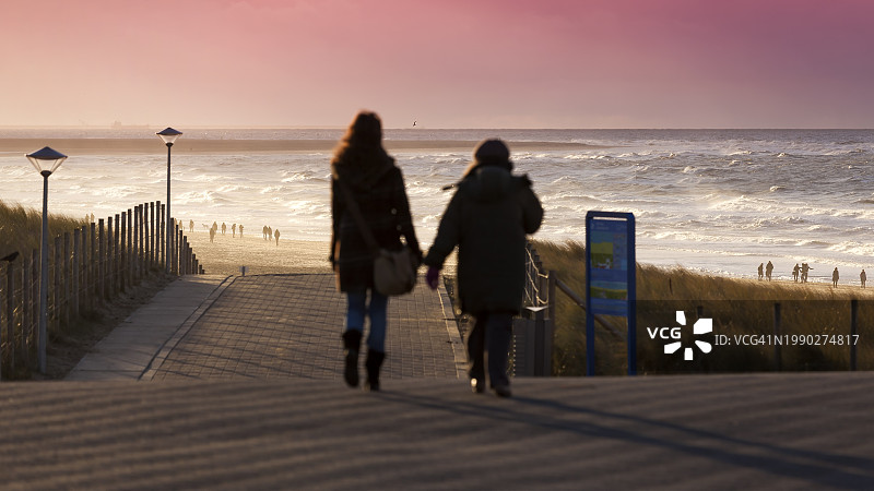 在Kijkduin林荫大道和海滩上冒着暴风雨行走的人群图片素材