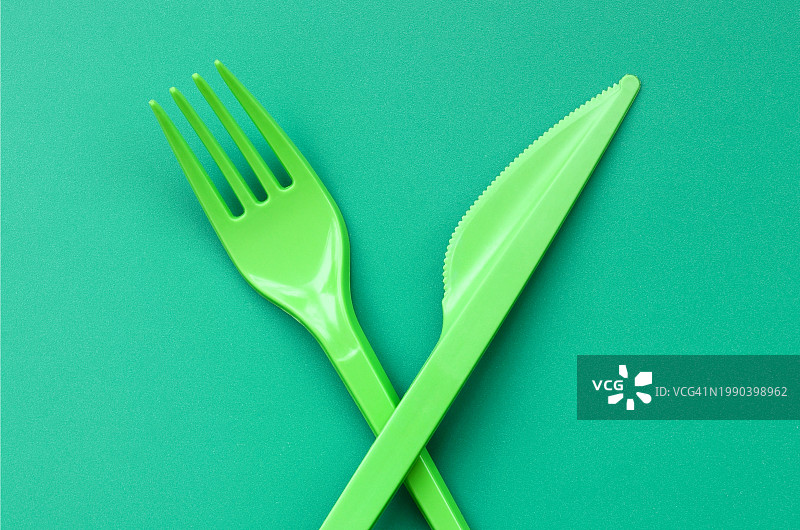 绿色背景上的塑料刀叉俯视图图片素材