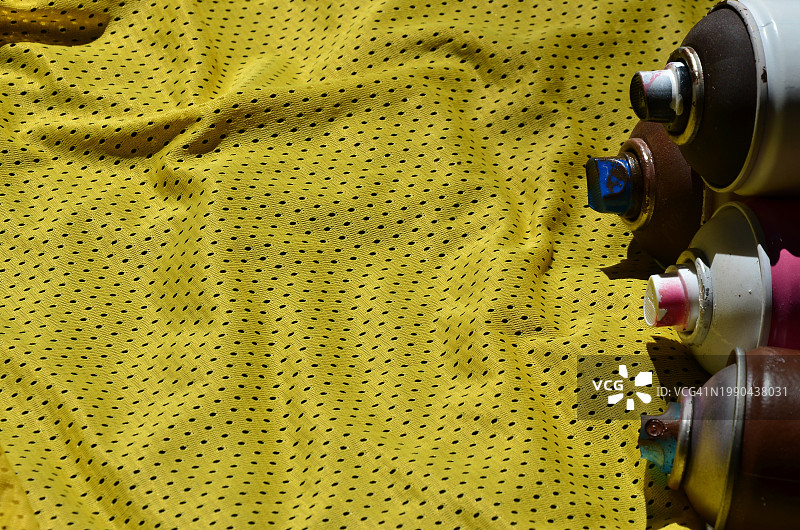 黄色纺织品上的气雾剂罐（高角度拍摄）图片素材