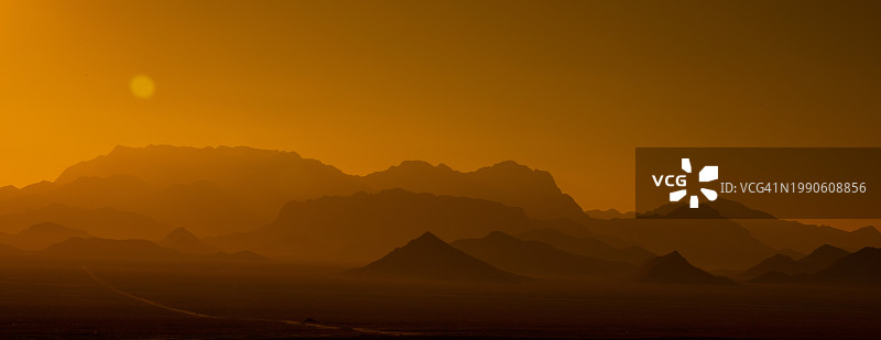 橙色天空映衬下群山剪影的美景图片素材