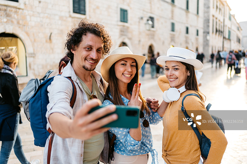 三个年轻朋友在杜布罗夫尼克广场自拍图片素材