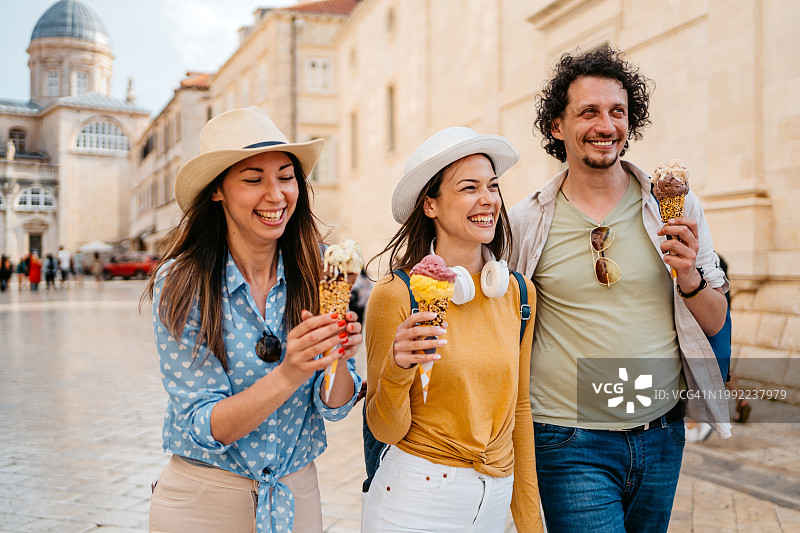 三个年轻的朋友在杜布罗夫尼克街上边走边吃冰淇淋图片素材