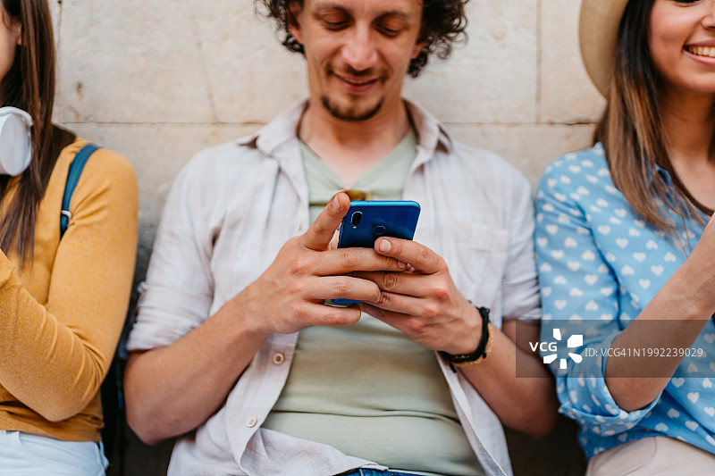 在杜布罗夫尼克坐在长凳上玩手机的三个年轻人图片素材