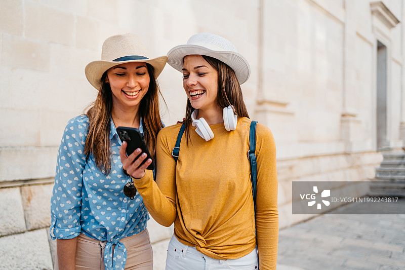 两个年轻女性朋友在杜布罗夫尼克街头边走边用手机图片素材