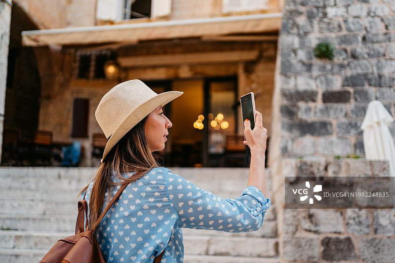 年轻女子在杜布罗夫尼克市中心广场用手机拍照图片素材
