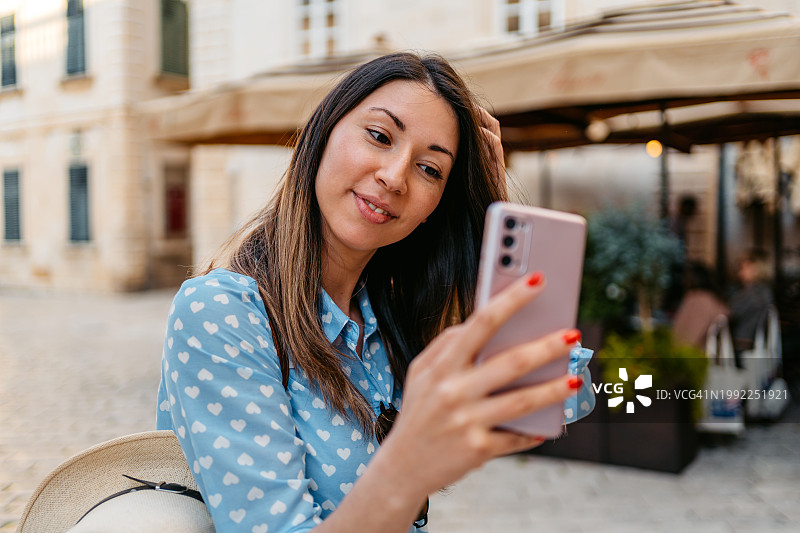 年轻女子在杜布罗夫尼克城镇广场用手机自拍图片素材