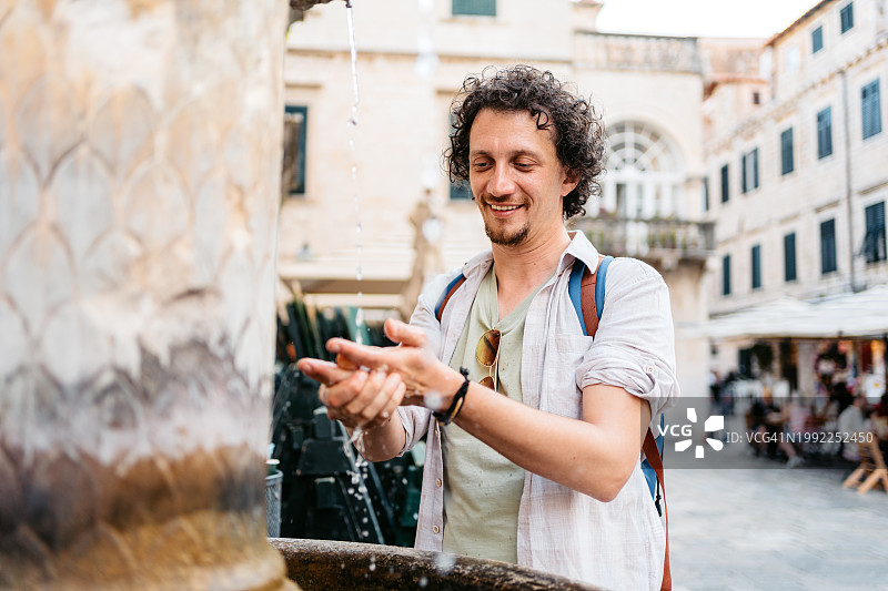 在杜布罗夫尼克喷泉洗手的年轻男人图片素材