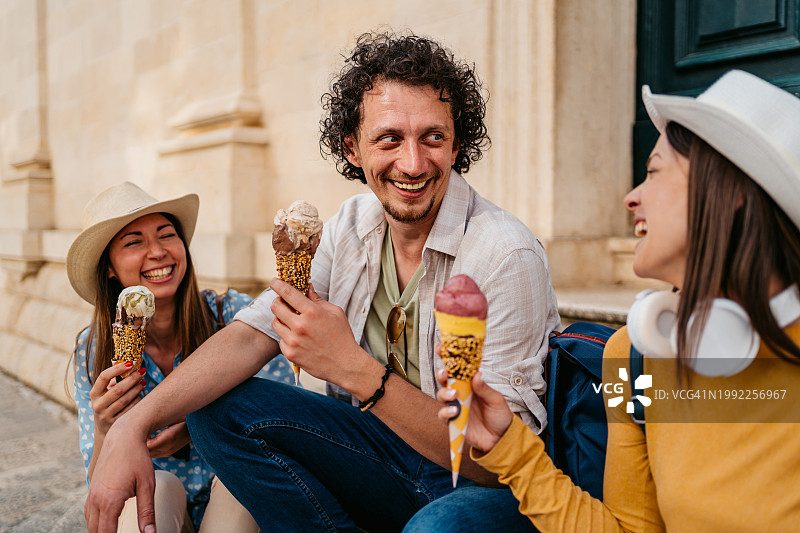 三位年轻朋友坐在杜布罗夫尼克的台阶上吃冰淇淋图片素材