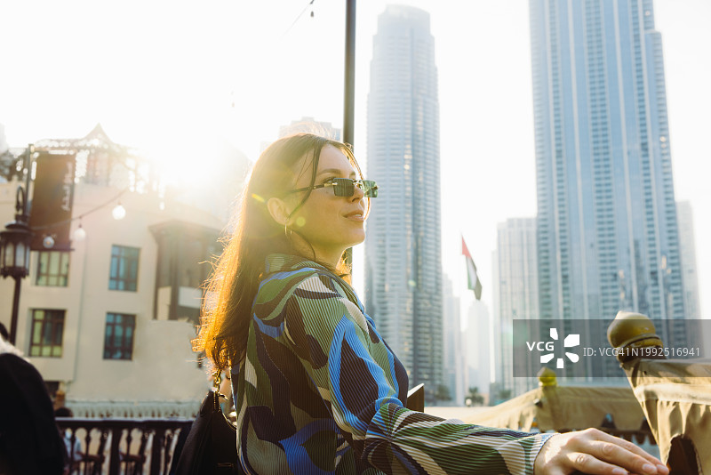 欣赏迪拜市中心摩天大楼壮丽日落的女人图片素材