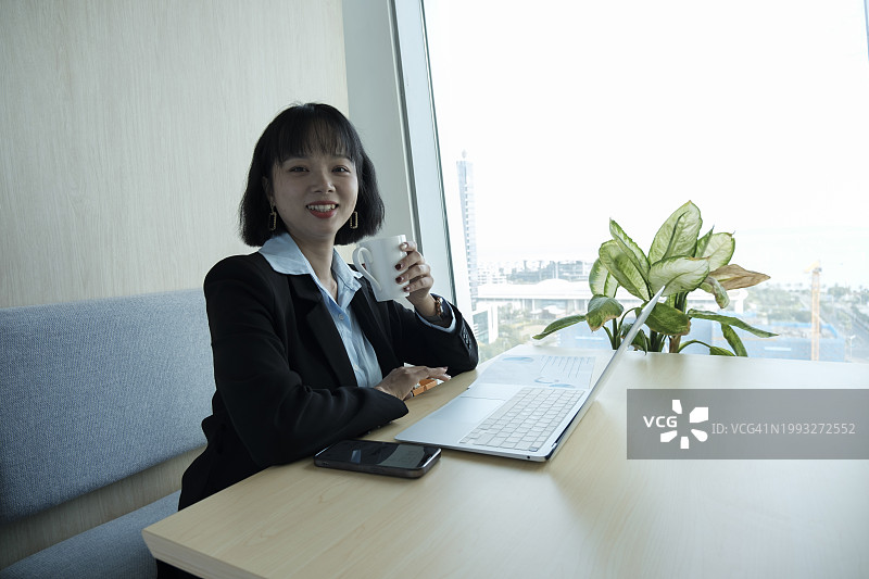 在办公室喝咖啡的微笑女商人图片素材