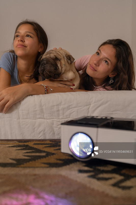 两个朋友和宠物一起用投影仪看电影图片素材