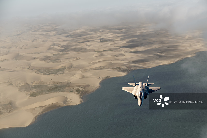 军用飞机飞越沙漠和海洋图片素材