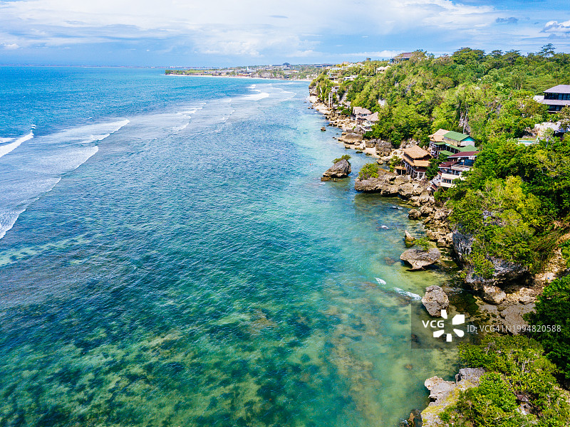 海岸景观航拍：碧蓝的海水、房屋和天空，巴厘岛布吉岛的宾银海滩图片素材
